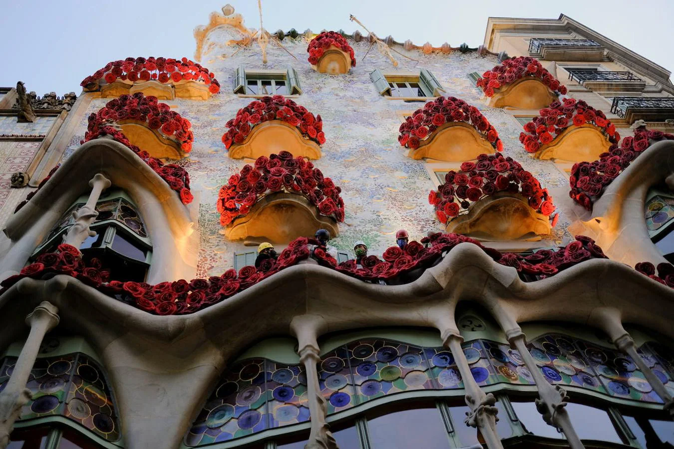 Trabajadores colocan rosas artificiales en el edificio diseñado por Gaudí. 