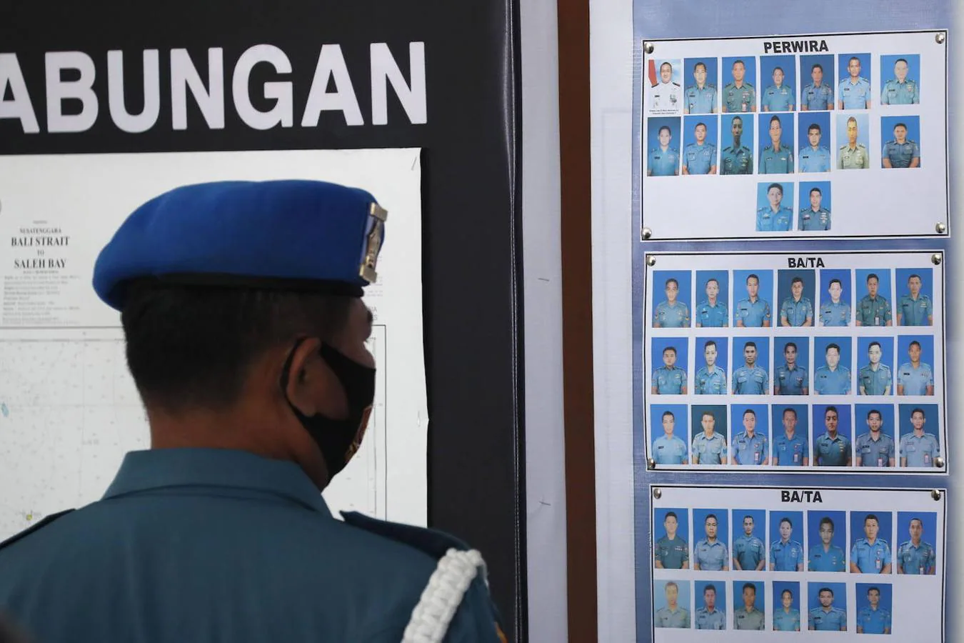 Un militar mira las fotografías de los miembros de la tripulación del submarino desaparecido de la Armada de Indonesia KRI Nanggala. 