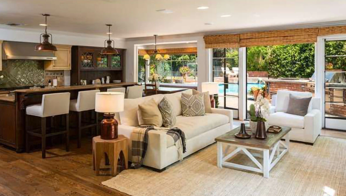 Así es la nueva mansión de Rihanna. La cocina, que incluye gabinetes de madera, electrodomésticos de acero inoxidable y una isla central con barra de desayuno y espacio extra de almacenaje, se abre a un comedor con sofás, que a su vez se abre al patio exterior.