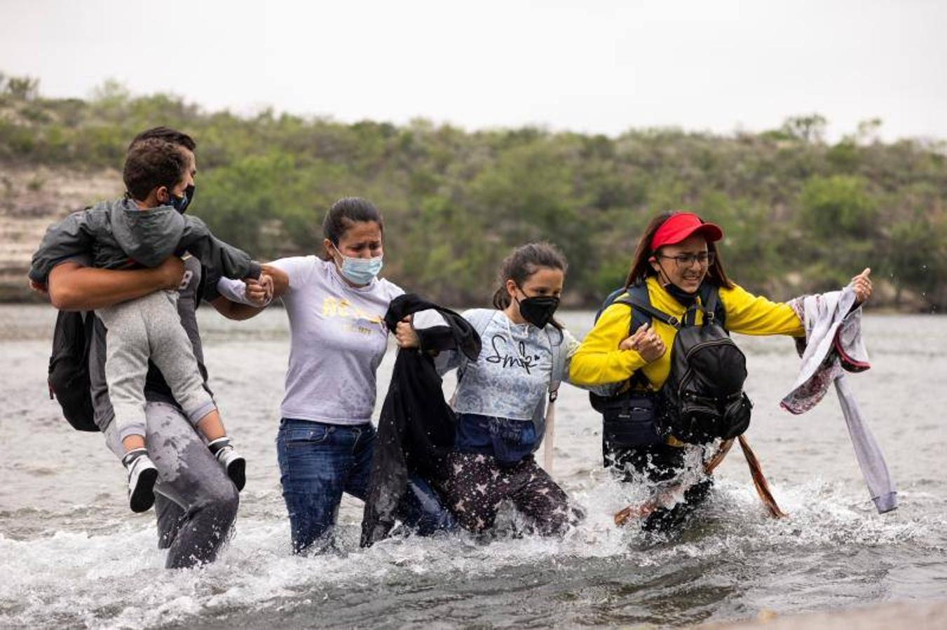 Un grupo de inmigrantes intenta cruzar de la mano las aguas del Río Bravo. 