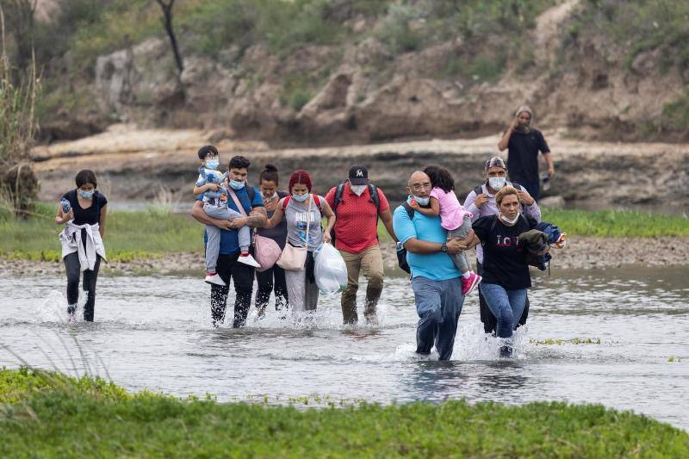 Un grupo numeroso de venezolanos vadea el río para llegar al otro lado de la frontera. 