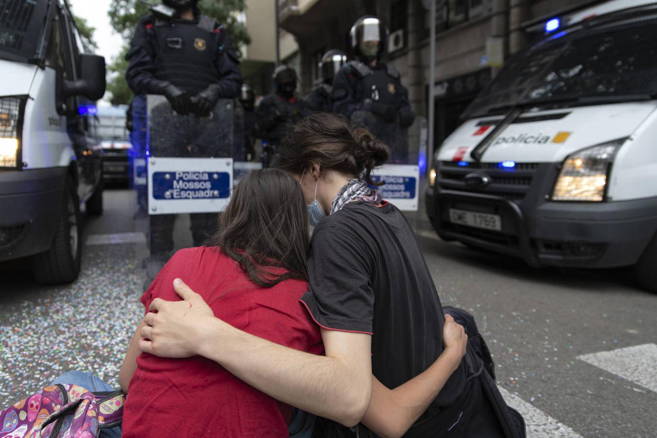 Dos mujeres sentadas y abrazadas frente a los Mossos d'Esquadra. 