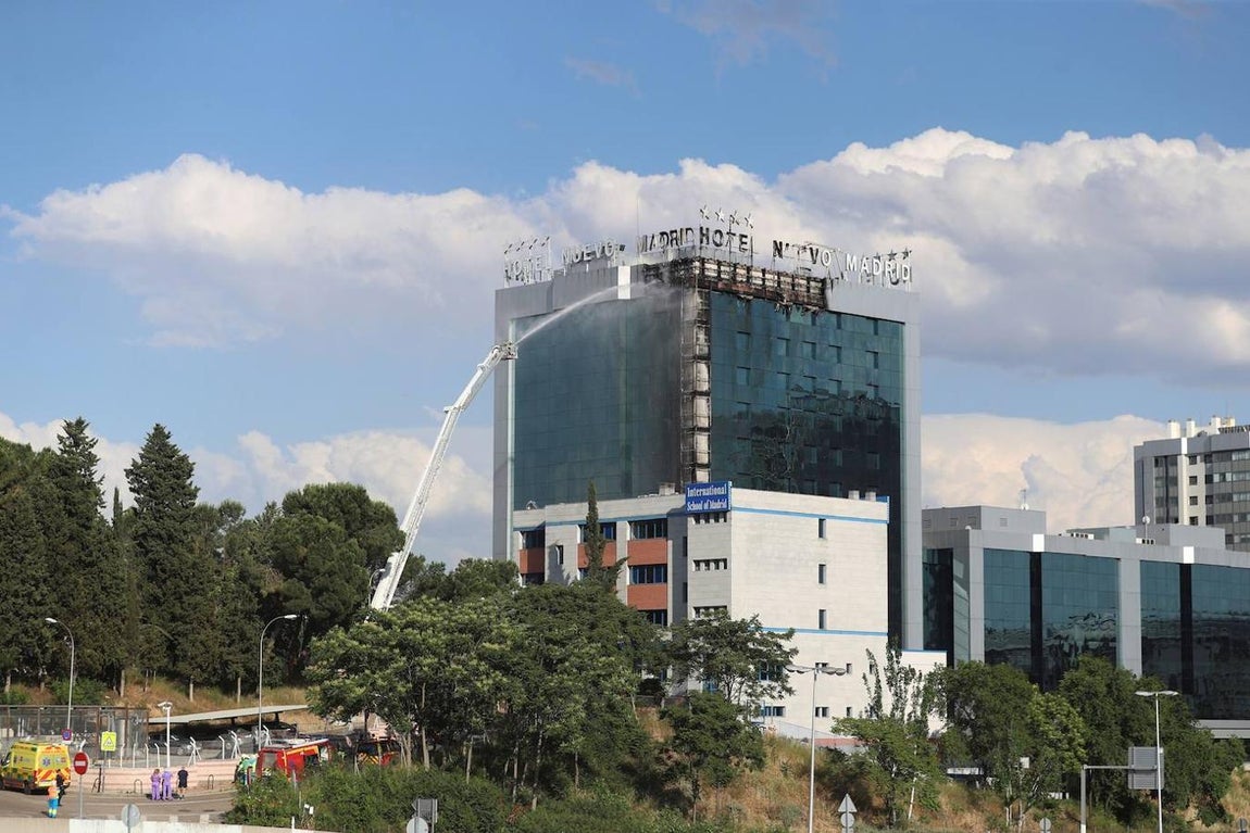 Bomberos extinguen las llamas tras un aparatoso incendio en la fachada exterior del Hotel Nuevo Madrid. 