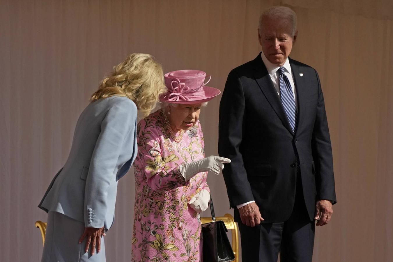 Ceremonia militar. Joe Biden, con traje de chaqueta azul, conversa con la Reina Isabel II, que eligió para la ocasión un vestido de flores rosa y pamela a juego