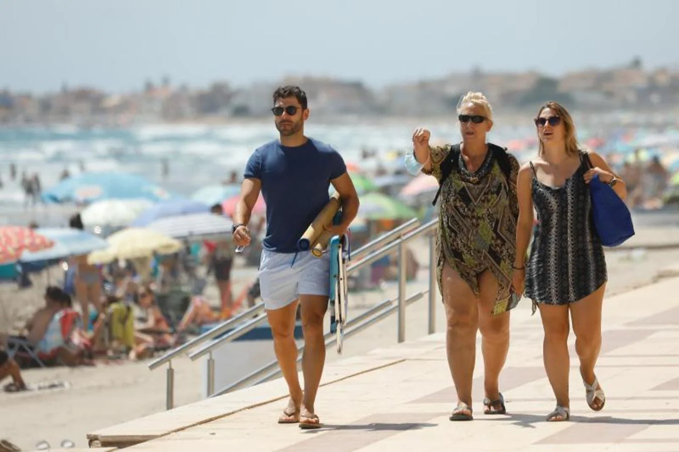 La relajación del uso de mascarilla al aire libre es mucho mayor en alas zonas costeras. En la imagen, tres personas caminan sin mascarilla, en el paseo marítimo de la playa de La Manga. 