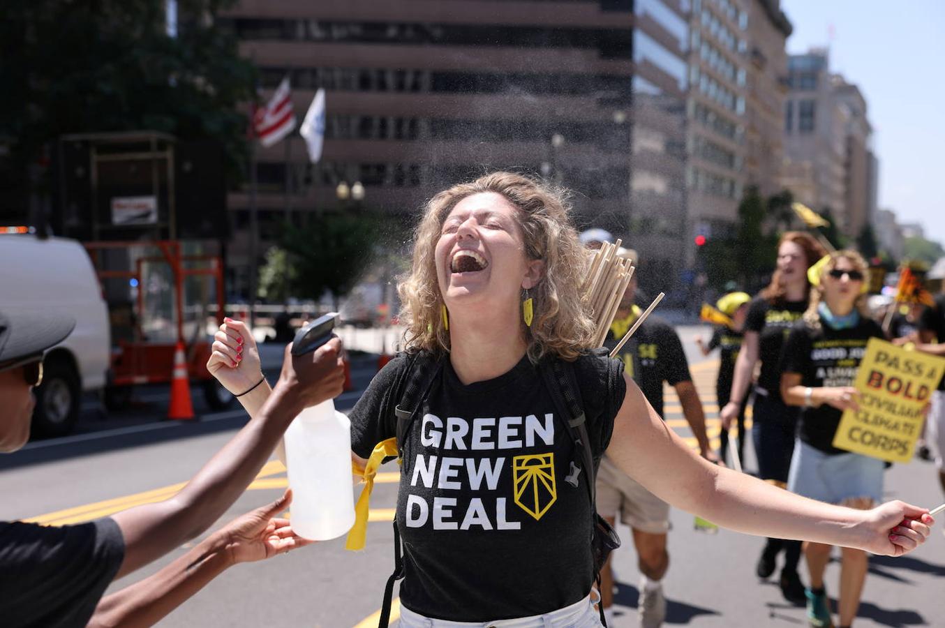 Una manifestante sonríe mientras se refresca con una botella de agua 'Sin clima, sin trato'  en Washington. 