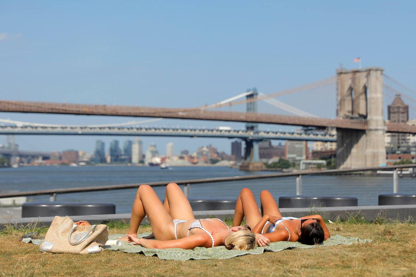 Dos mujeres toman el sol frente al Puente de Brooklyn. 