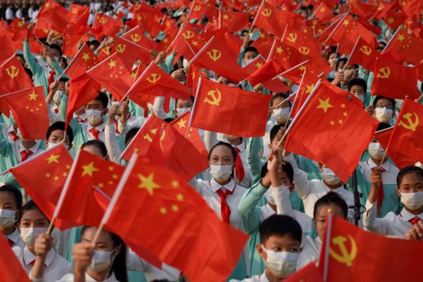 Los estudiantes ondean banderas de China y del Partido Comunista de China antes de las celebraciones en Beijing el 1 de julio de 2021. 