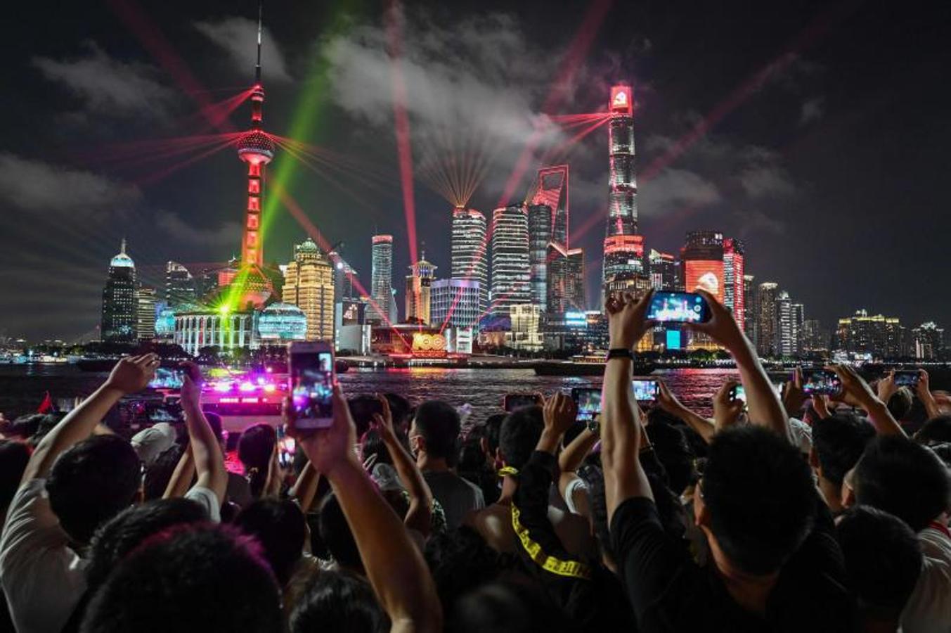 Las personas toman fotografías mientras miran un espectáculo de luces en el paseo del Bund en Shanghai el 30 de junio de 2021, en vísperas del centenario del Partido Comunista Chino. 