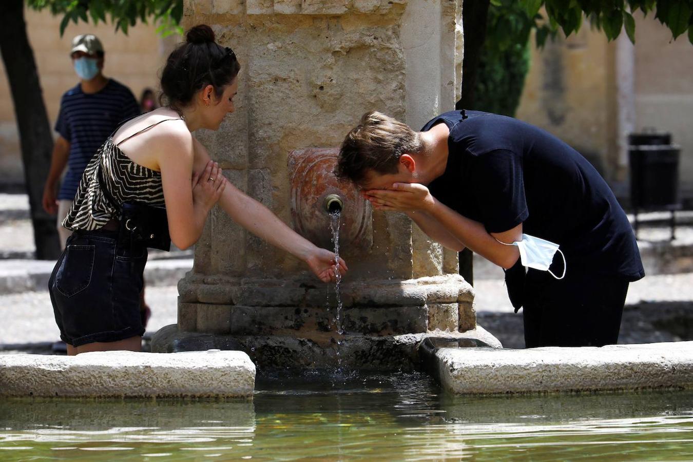 Varias personas se refrescan en una fuente para intentar sofocar las altas temperaturas (Córdoba). 