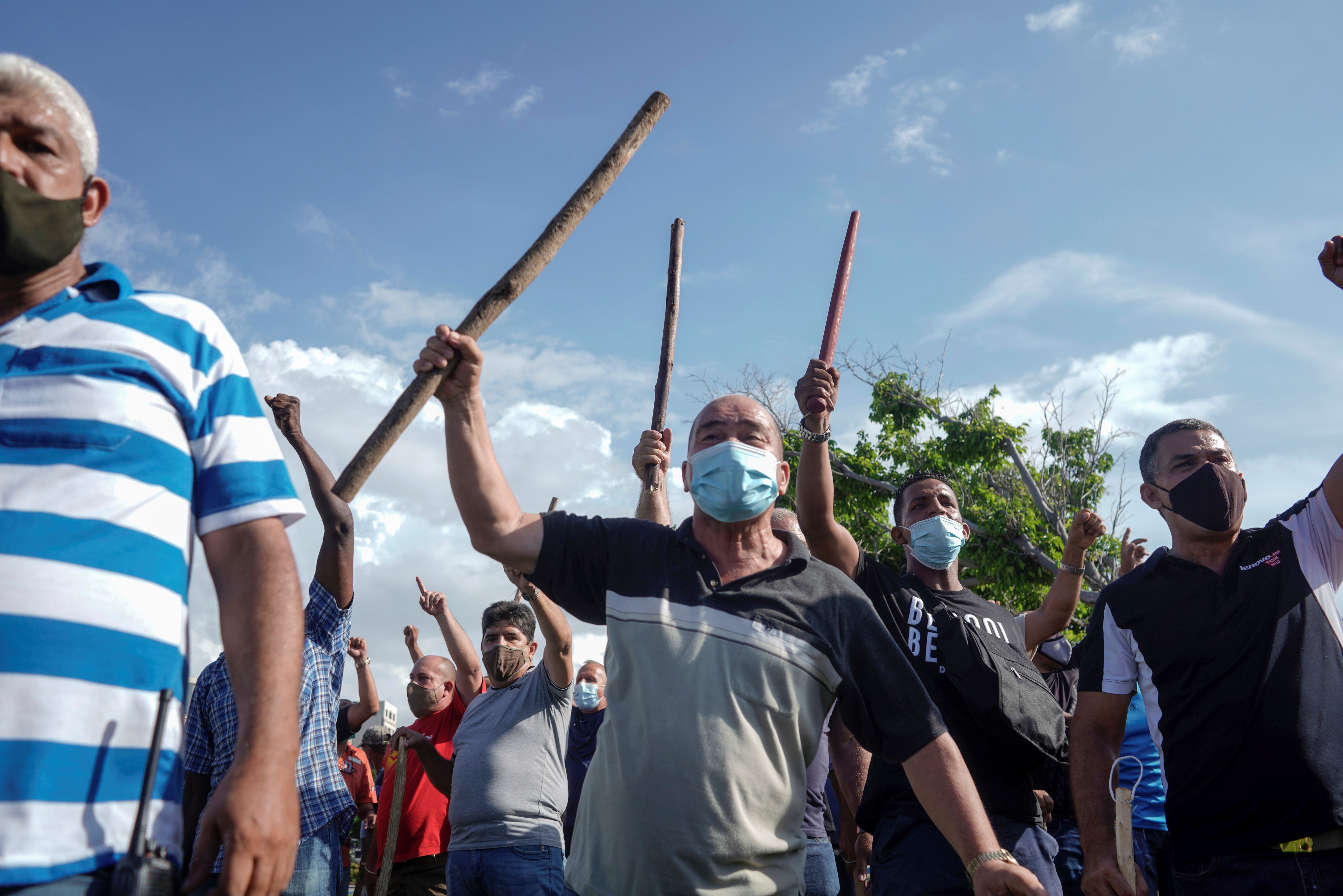 Manifestantes sostienen palos de madera en la mano. 