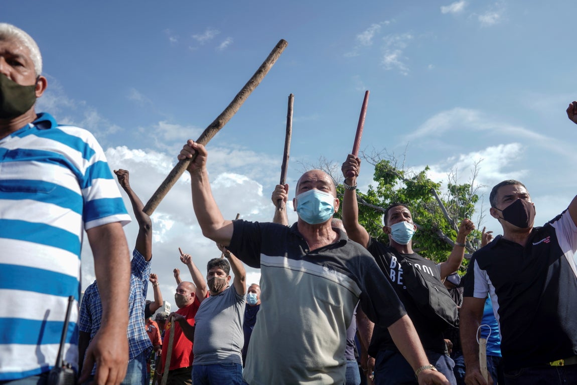Manifestantes sostienen palos de madera en la mano. 