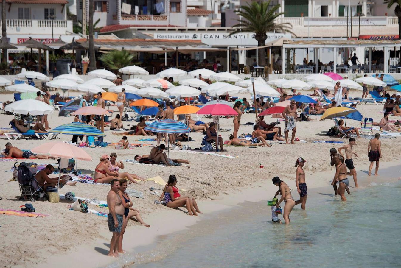 Varios bañistas disfrutan de una soleada jornada en la playa de Punta Prima de Menorca, donde permanece activa la alerta naranja por la ola de calor. 