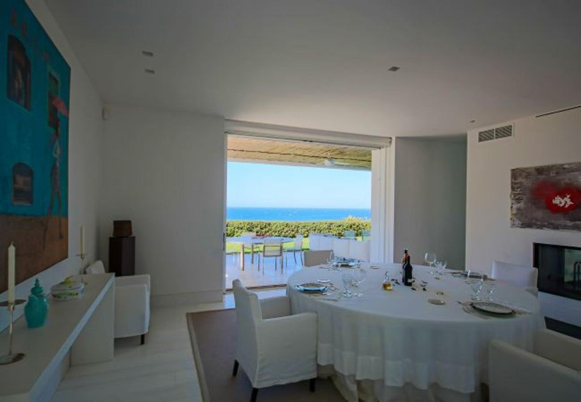 La lujosa villa que Sara Carbonero ha alquilado en Cádiz. El comedor comunica con el salón, el jardín y la cocina, donde una gran mesa redonda blanca se hace con el protagonismo. Otro detalle que habría que mencionar del exterior es la zona de huerto privado, el riachuelo y su acceso directo a la playa a través de un puente de madera.