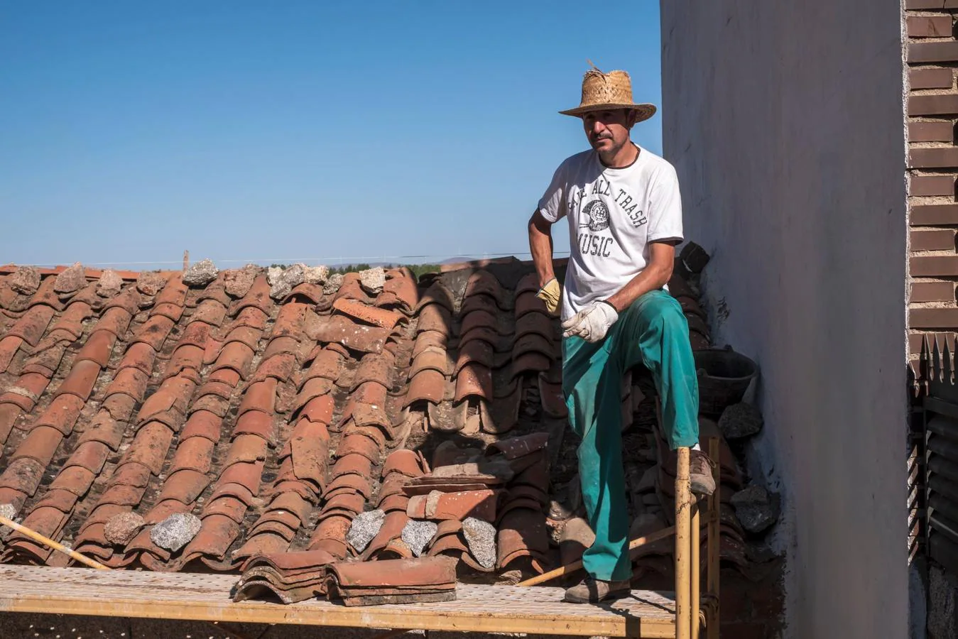 El vecino de Villaviciosa David Martín, que coloca tejas en la techumbre de su casa
