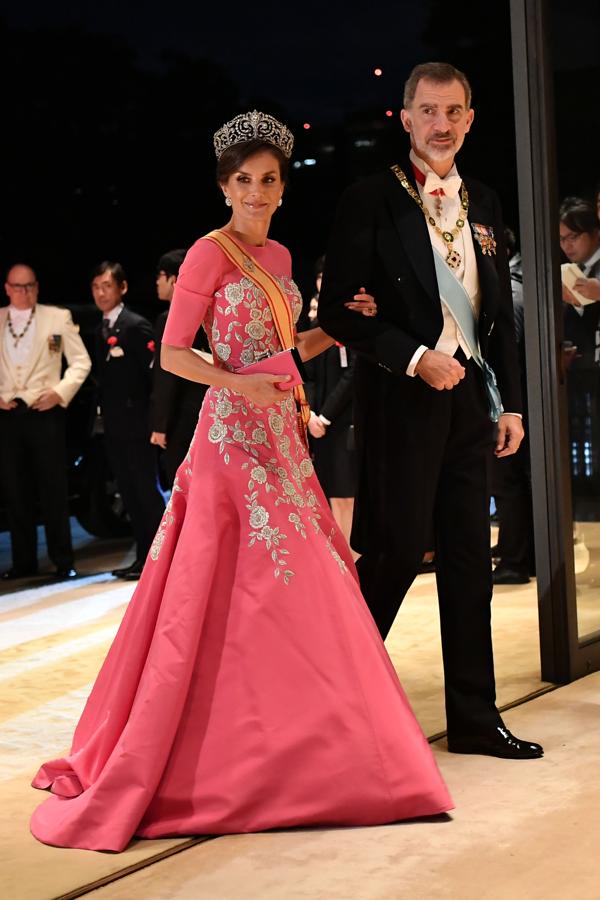 2019 - Los vestidos más icónicos de la Reina Letizia. En la Cena de gala tras la ceremonia de entronización del emperador Naruhito de Japón lució uno de sus estilismos más coloridos con un vestido rosa fucsia de Carolina Herrera al que añadió la tiara de la flor de Lis. Dicha pieza la estrenó en 2017 y se trata de una de las más valiosas de su joyero, pues fue un regalo de Alfonso XIII a su prometida, Victoria Eugenia de Battemberg, quien la llevó en su boda, el 31 de mayo de 1906.