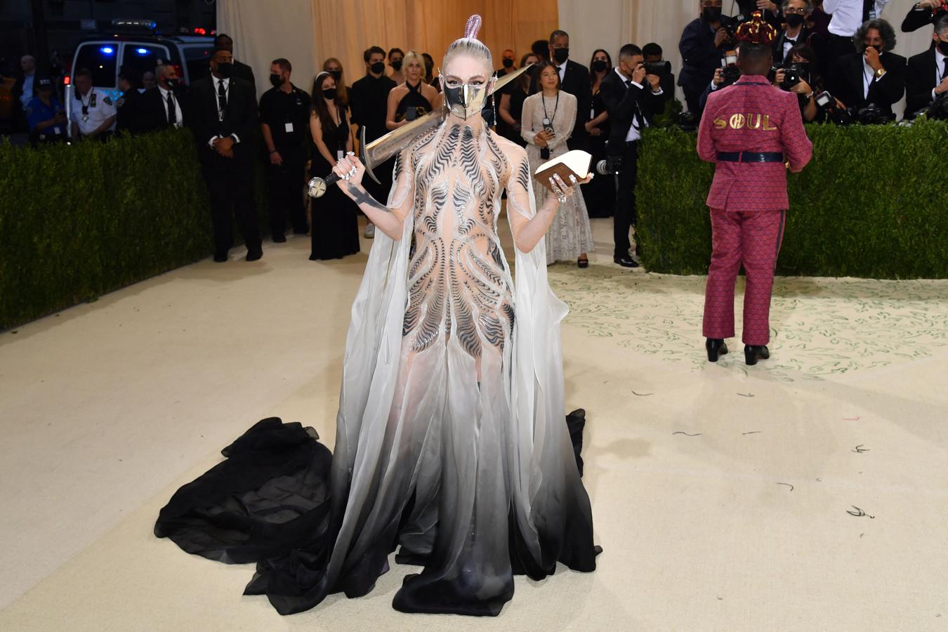 Grimes - Alfombra roja de la Gala MET 2021. Luió un look fe aires futuristas de Iris Van Herpen. Un vestido con bordados tridimensionales que terminaba en unna falda con caída y degradado en gris.