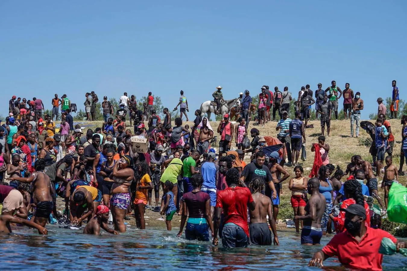 Varios migrantes haitianos, que forman parte de un grupo de más de 10.000 personas que se alojan en un campamento en el lado estadounidense de la frontera, cruzan el Río Grande para obtener comida y agua en México. 