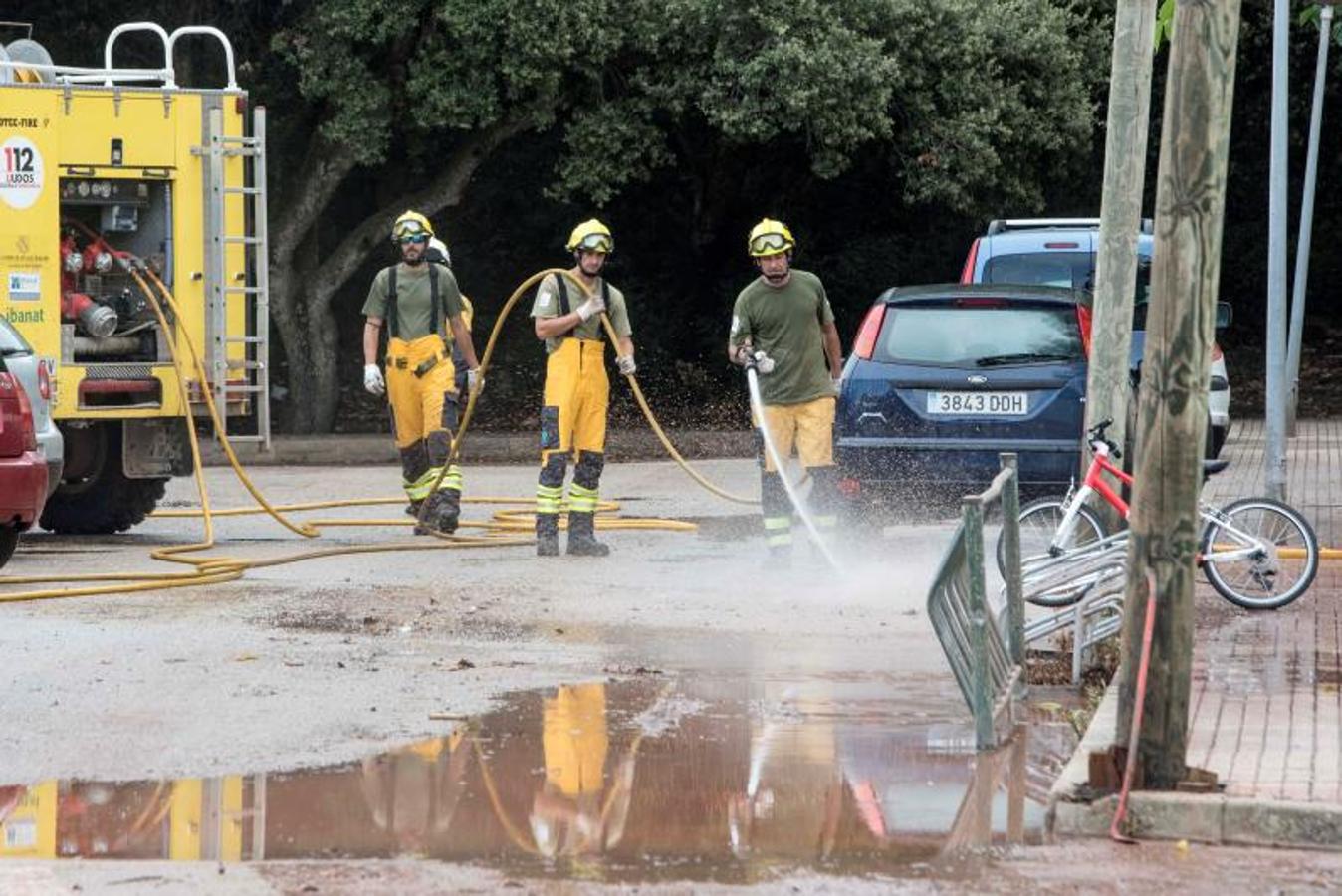 Miembros del IBANAT limpian las calles del fango acumulado tras el desbordamiento del torrente, en Ferreries. 