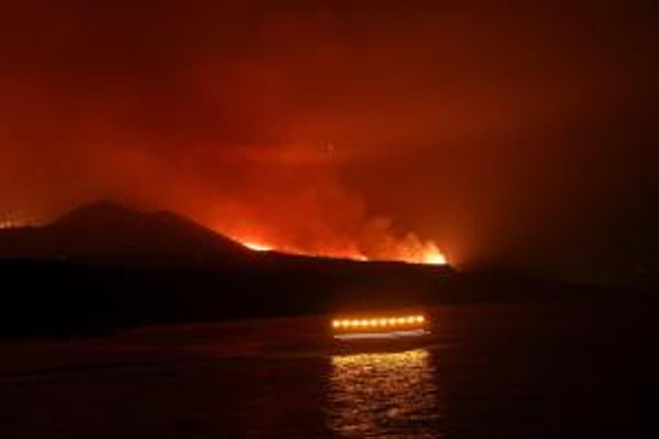 Los guardacostas pasan, mientras la riada formada por la colada llega al mar en el puerto de Tazacorte. 