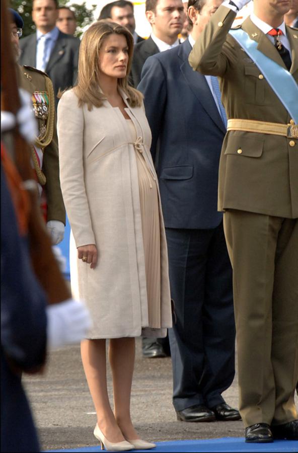 2005 - Los looks de la Reina Letizia en el Día de la Hispanidad. Embarazada de la princesa Leonor, llevó un vestido midi beige de Felipe Varela con falda plisada y abrigo del mismo color que conjuntó con salones de Magrit.