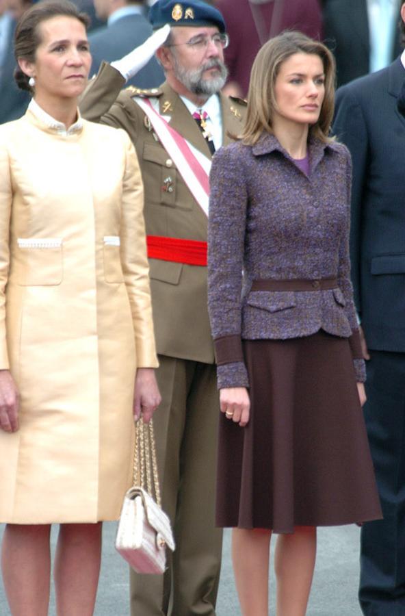 2004 - Los looks de la Reina Letizia en el Día de la Hispanidad. La primera vez que asistió al desfile se decantó por un dos piezas de Felipe Varela con falda color chocolate acampanada y una chaqueta de tweed de ese mismo color y púrpura.