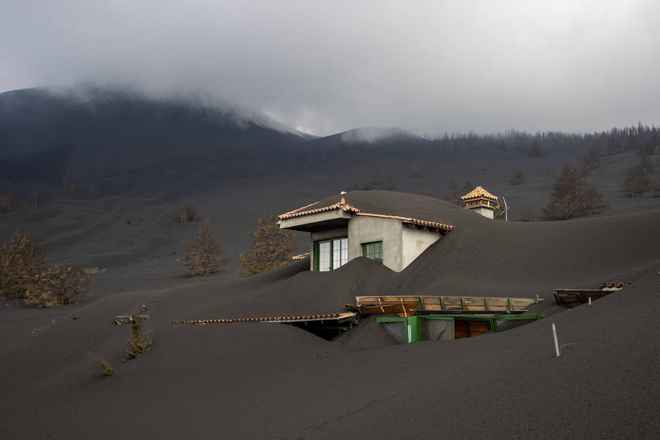 Casa de Iván San Blas en la carretera de San Nicolás, prácticamente enterrada. Iván pide encarecidamente que le dejen entrar en la zona a limpiar los tejados y que su casa, donde ha invertido toda su vida y ahorros, no se hunda con el peso de las cenizas que la cubren prácticamente en su totalidad. 