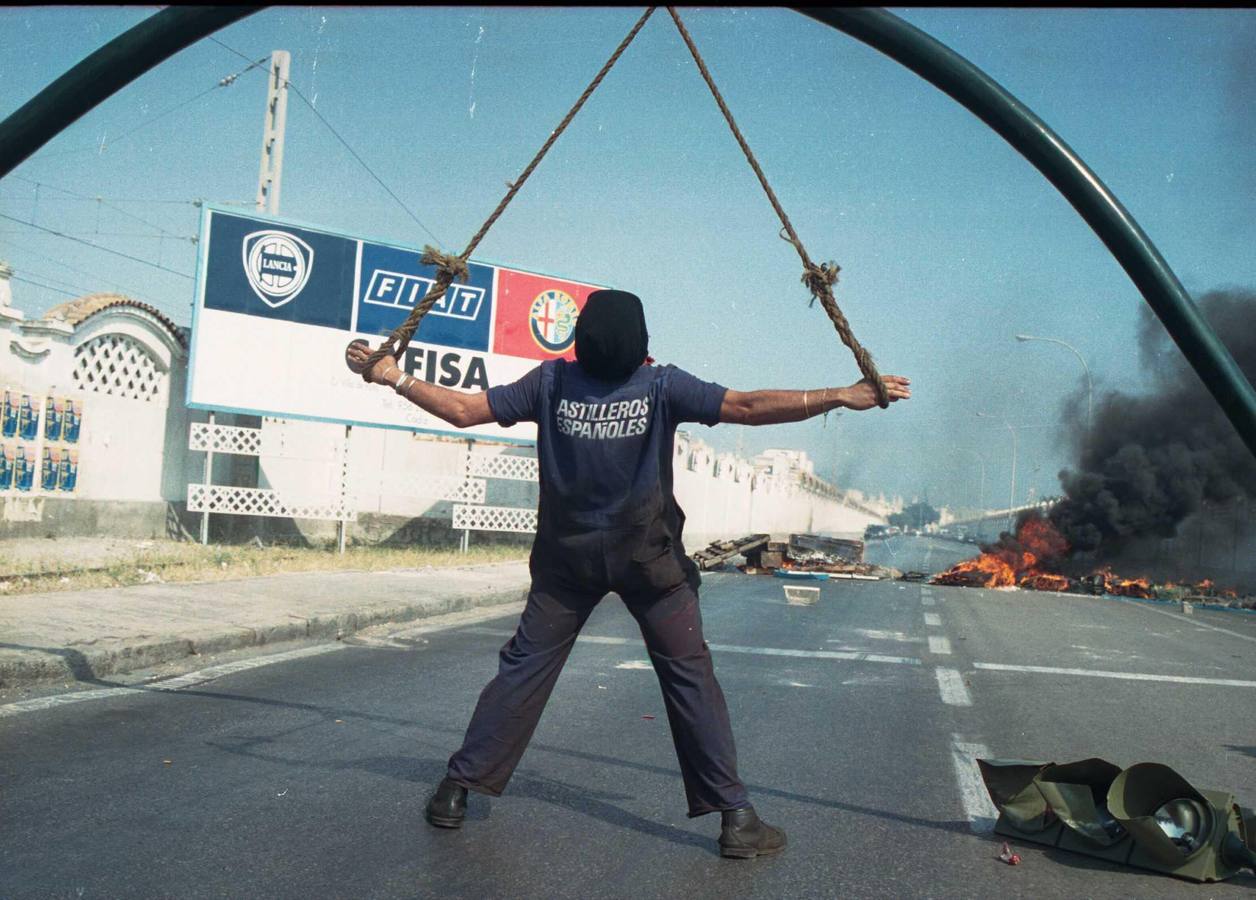 Un trabajador protesta simulando estar amarrado en la carretera industrial de la capital de Cádiz. 