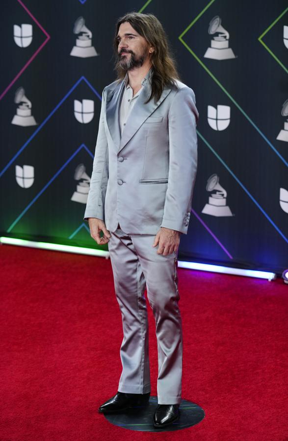 Juanes - Alfombra roja de los Grammy Latinos 2021. Para posar en el red carpet se decantó por un traje de aires retro en gris perla con acabado satinado mientras que para recoger su galardón eligió uno en azul eléctrico más llamativo.