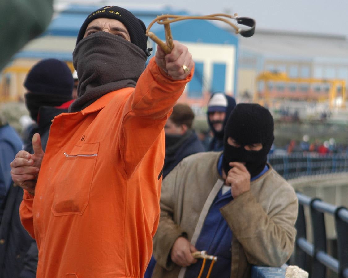 Un trabajador lanza una piedra con una honda ataviado con un gorro del Cádiz CF. 