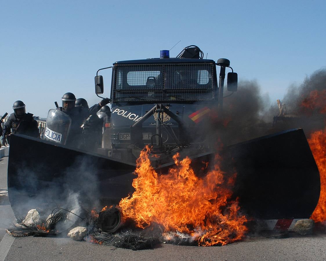 Un vehículo policial equipado con pala supera una barricada incendiada. 