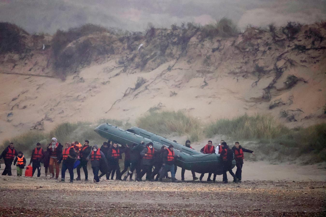 Ataviados con gorros de lana y abrigos, algunos incluso con chalecos salvavidas rojos, unos 15 migrantes arrastraron el bote de goma sobre sus hombros y cabezas. 