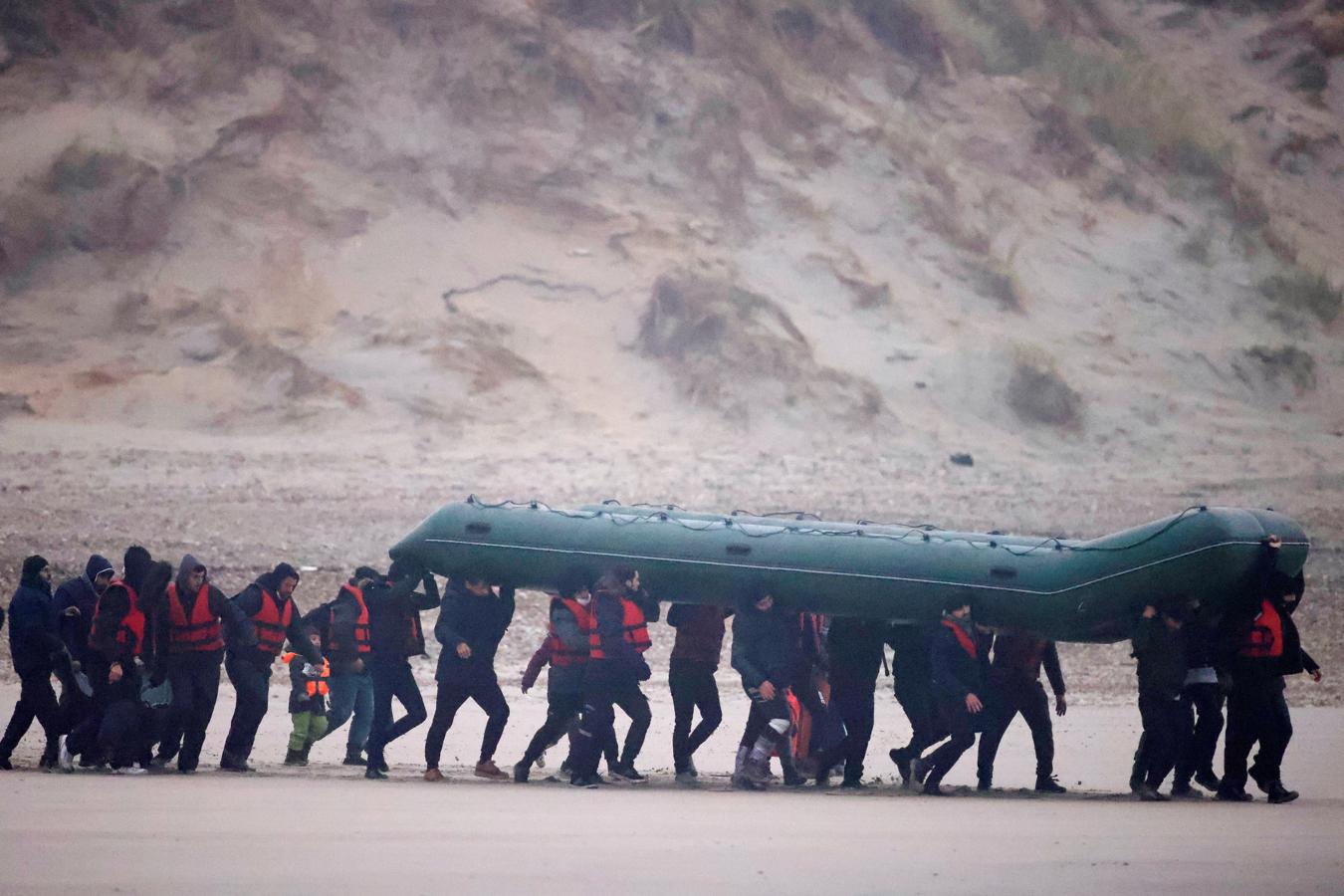 Los inmigrantes caminan sobre las dunas hacia la playa mientras sus familias los seguían con sus hijos. 