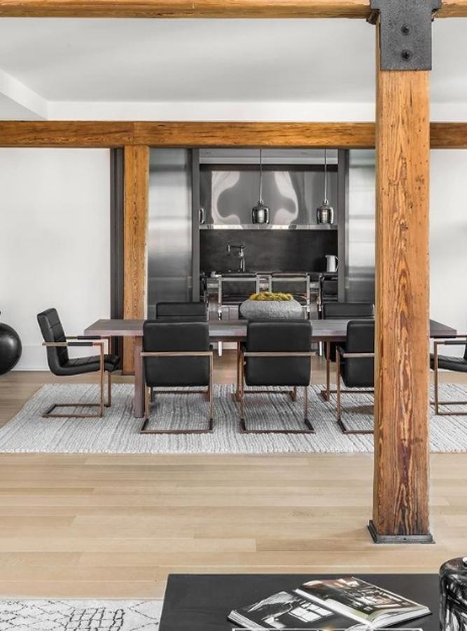 El ático que Lewis Hamilton ha vendido en Nueva York. La cocina se dispone en tonos negros y grises y comunica con el comedor por una puerta corredera, donde una gran mesa preside el espacio.