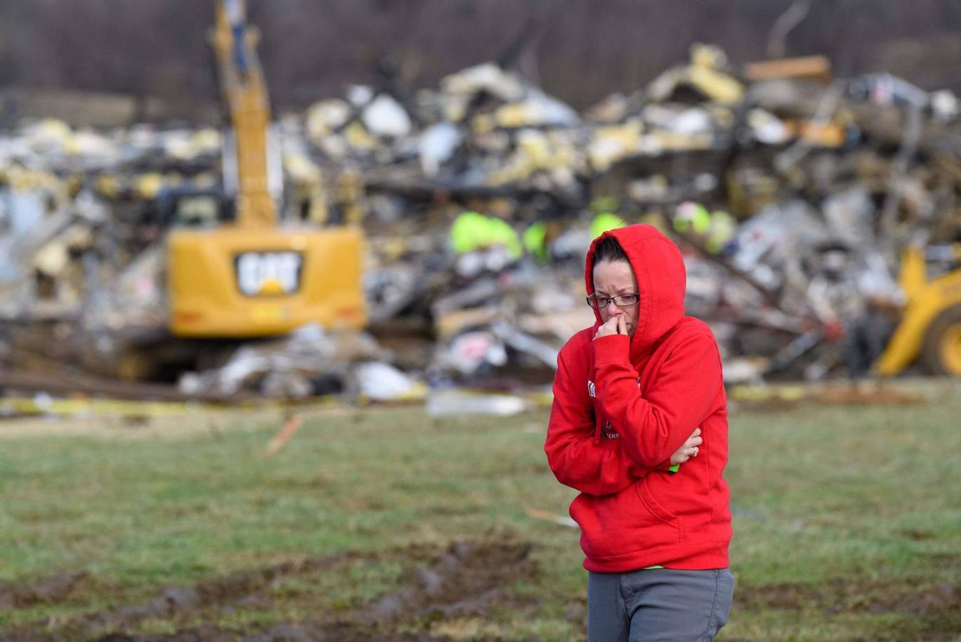 Una mujer se aleja de lo que queda de Mayfield Consumer Products Candle Factory mientras los trabajadores de emergencia peinan los escombros después de que fue destruido por un tornado en Mayfield, Kentucky, el 11 de diciembre de 2021. 