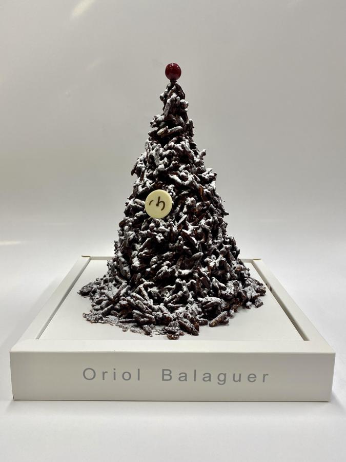 Árbol de Navidad de Oriol Balaguer. El maestro pastelero presenta como cada temporada una nueva colección para apasionados del dulce: porciones dePanettone bañadas en Chocolate Negro, esculturas en forma de Abeto o nuevas Tabletas de autor. Detalles deliciosos y exquisitos perfectos para regalar y disfrutar, como esta escultura de Abeto, elaborados a partir de cookies de Chocolate y conselección de frutos secos como Almendras, que Balaguer finaliza con perlas crujientes, coronando la copa del Árbol. Precio: 75€