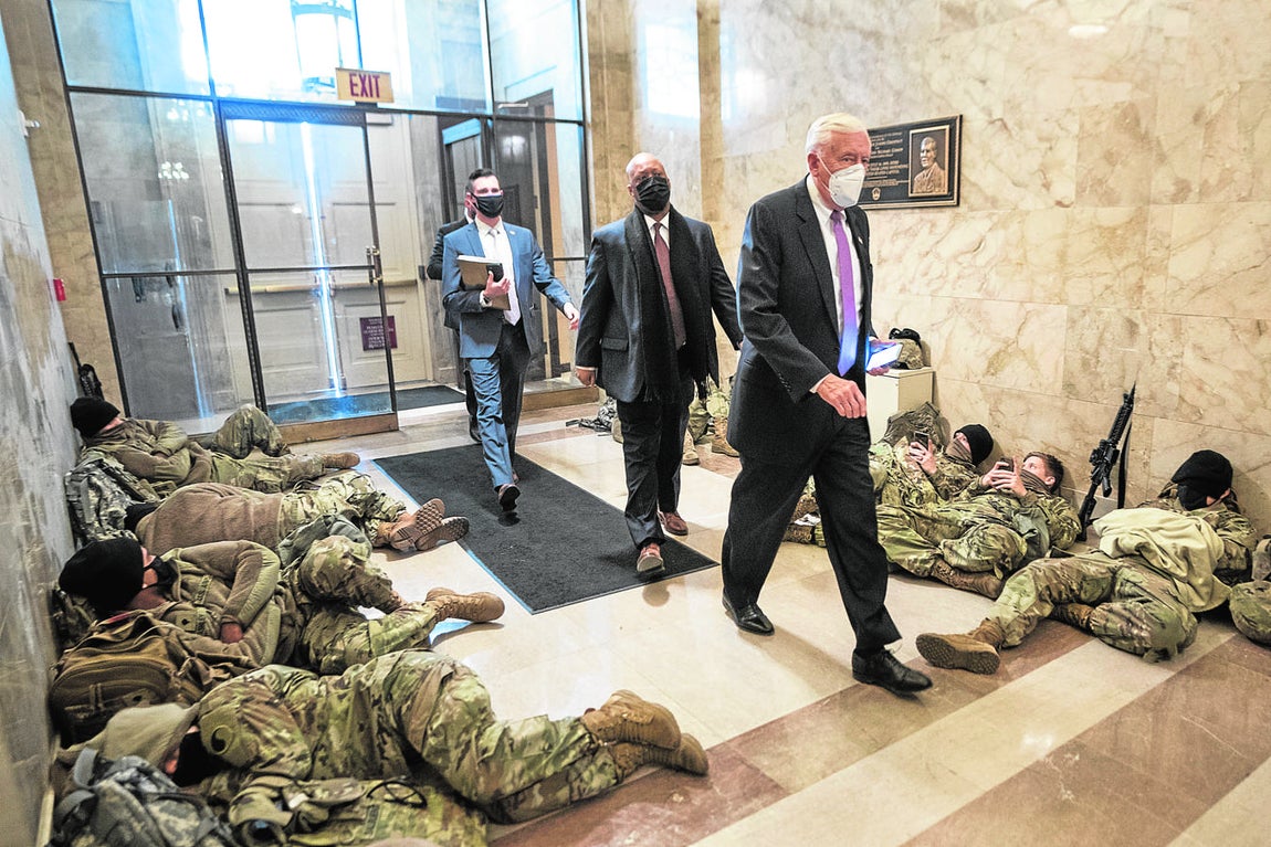 El líder de la mayoría Steny Hoyer pasa junto a miembros de la Guardia Nacional que intentan dormir un poco dentro del Capitolio de los EE. UU.. 