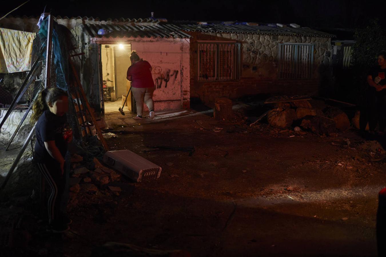 Una mujer limpia mientras su hija juega en la entrada de la casa. 