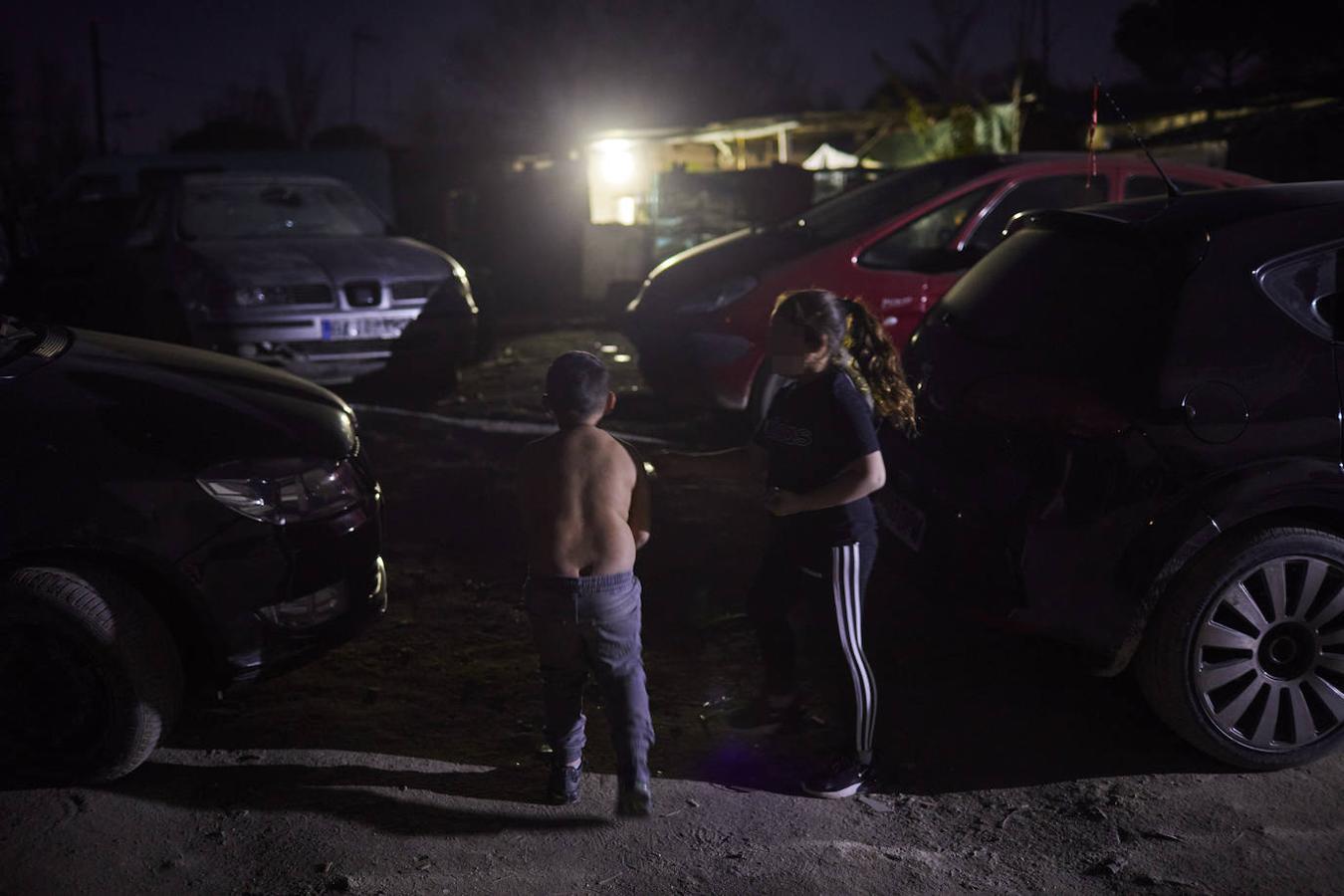 Dos menores juegan de noche junto a la calle de Esteban García, el camino de polvo, baches y barro que vertebra el asentamiento de Las Sabinas. 