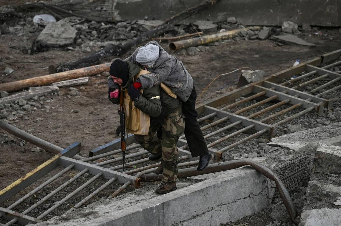 Un soldado carga a su espalda a un ciudadano de Irpin. 