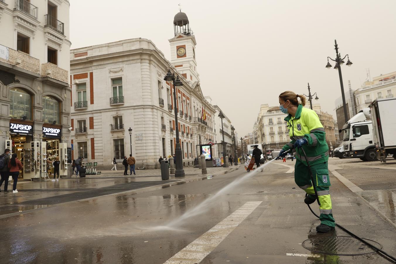 Limpieza en Madrid. Trabajadores de la limpieza retiran en la Puerta del Sol el polvo en suspensión que proviene del Sáhara que tras la lluvia acaecida en Madrid este martes ha teñido la ciudad de un color naranja