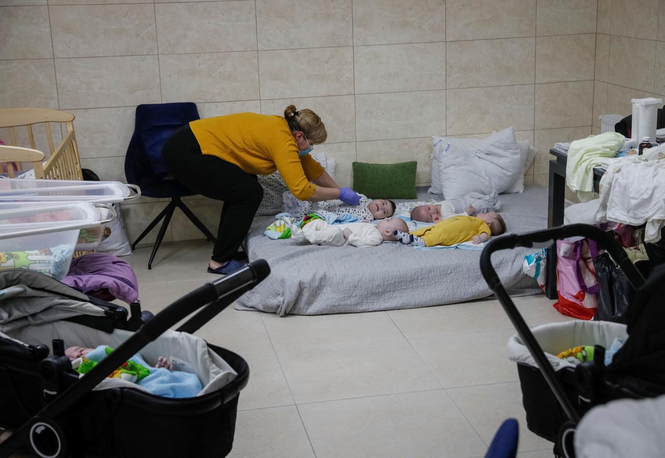 Una enfermera cuida de unos niños que descansan en un colchón. 