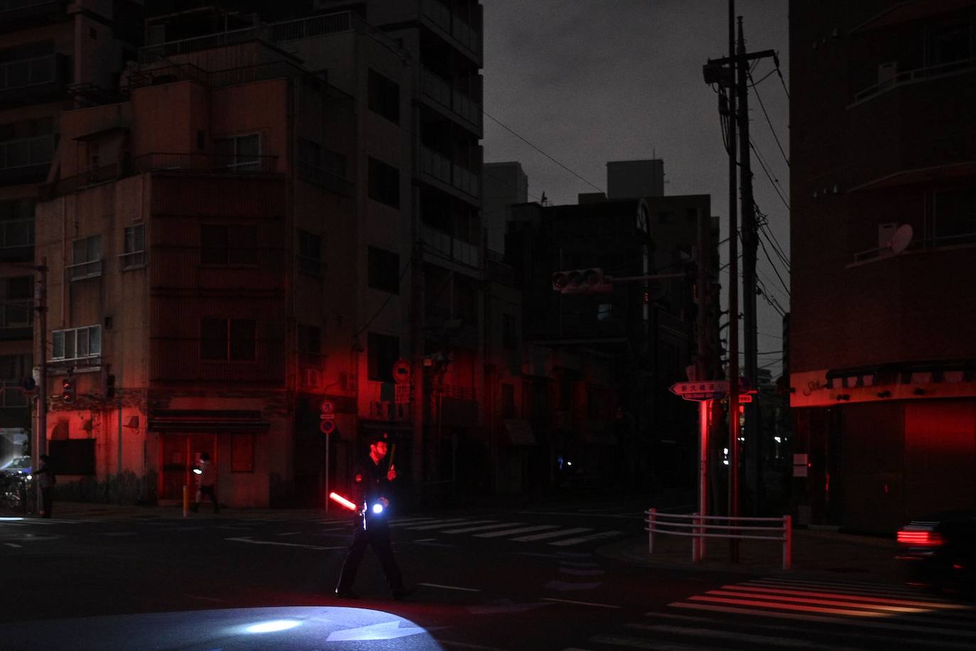 Un policía patrulla por un calle sin suministro eléctrico en Tokio