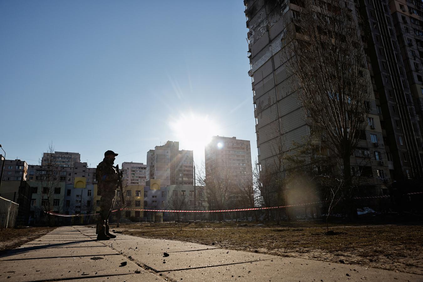 Un soldado ucraniano hace guardia junto a un edificio atacado por Rusia. 