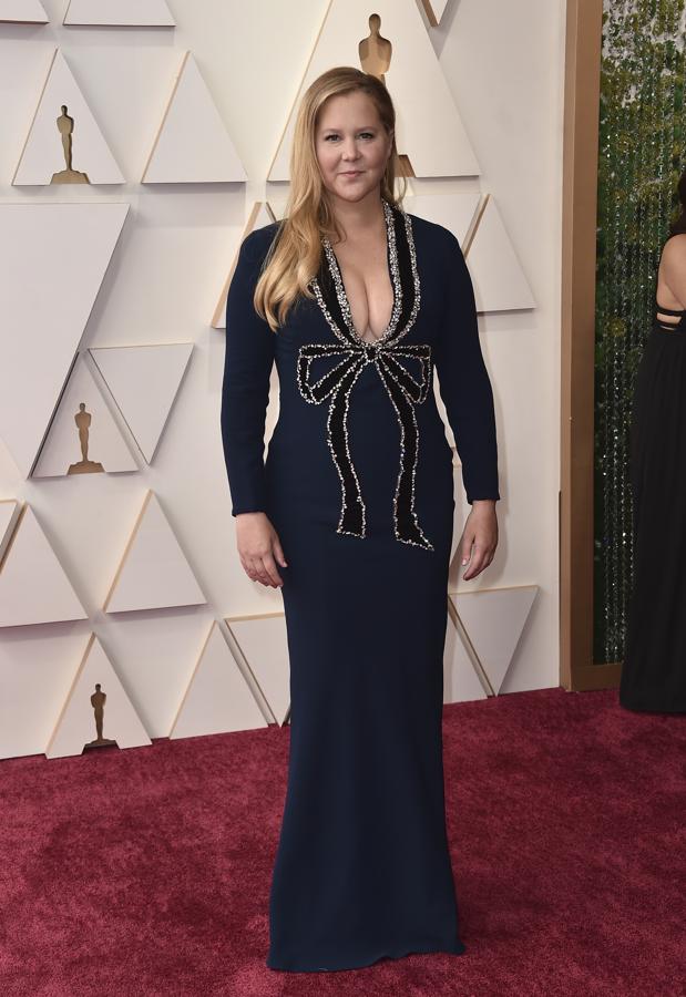 Amy Schumer - Las peor vestidas de los Oscar 2022. El lazo de su diseño de Oscar de la Renta recuerda a los adornos navideños y hace que el modelo pierda todo el buen gusto que podría haber tenido gracias a su elegante corte y el color.