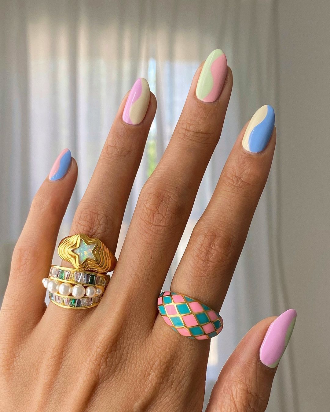 Manicura en tonos pastel y ondas. Elegir los esmaltes de color pastel es un acierto para esta primavera. Esta manicura multicolor combina dos tonos candy en cada una con un elegante diseño ondulado. (Instagram @overglowedit).
