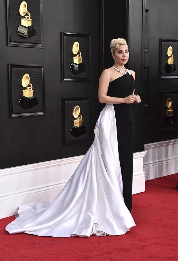Lady Gaga - Alfombra roja de los Grammy 2022. Lució un vestido bicolor con escote asimétrico y una voluminosa cola satinada de Armani Privé al que añadió joyería de Tiffany &amp; Co.