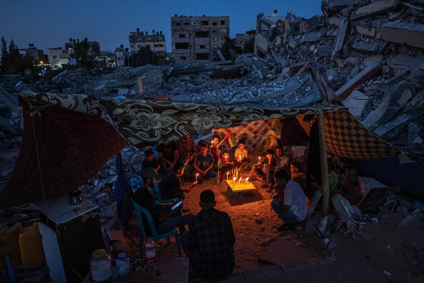 Niños palestinos en Gaza. Niños palestinos se reúnen con velas durante un frágil alto el fuego en Beit Lahia, Gaza, Palestina, el 25 de mayo de 2021, tras una protesta de los niños del barrio contra los ataques a Gaza. El conflicto, que duró 11 días, estalló el 10 de mayo, a raíz de las crecientes tensiones. Se dispararon cohetes a través de las fronteras con Siria y Líbano, en lo que se convirtió en el brote más intenso de enfrentamientos desde la Guerra de Gaza de 2014. UNICEF declaró que unos 500.000 niños de Gaza podrían necesitar apoyo psicológico.