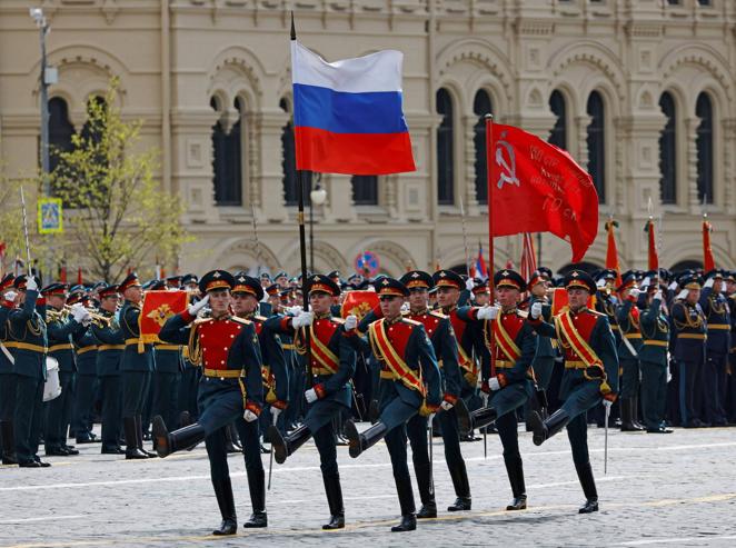 Un grupo de soldados portan la bandera rusa y la comunista. 