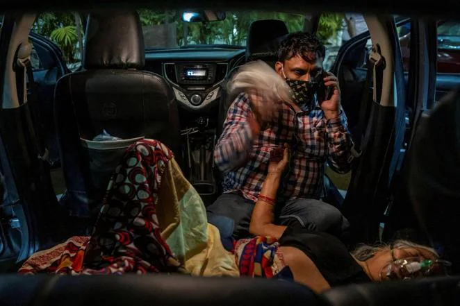 Un hombre, Manoj Kumar, agita un pañuelo desde el asiento trasero de su vehículo para abanicar a su madre, Vidhya Devi, mientras recibe oxígeno en el estacionamiento de un Gurudwara (un templo sij), en Ghaziabad, el 24 de abril de 2021
